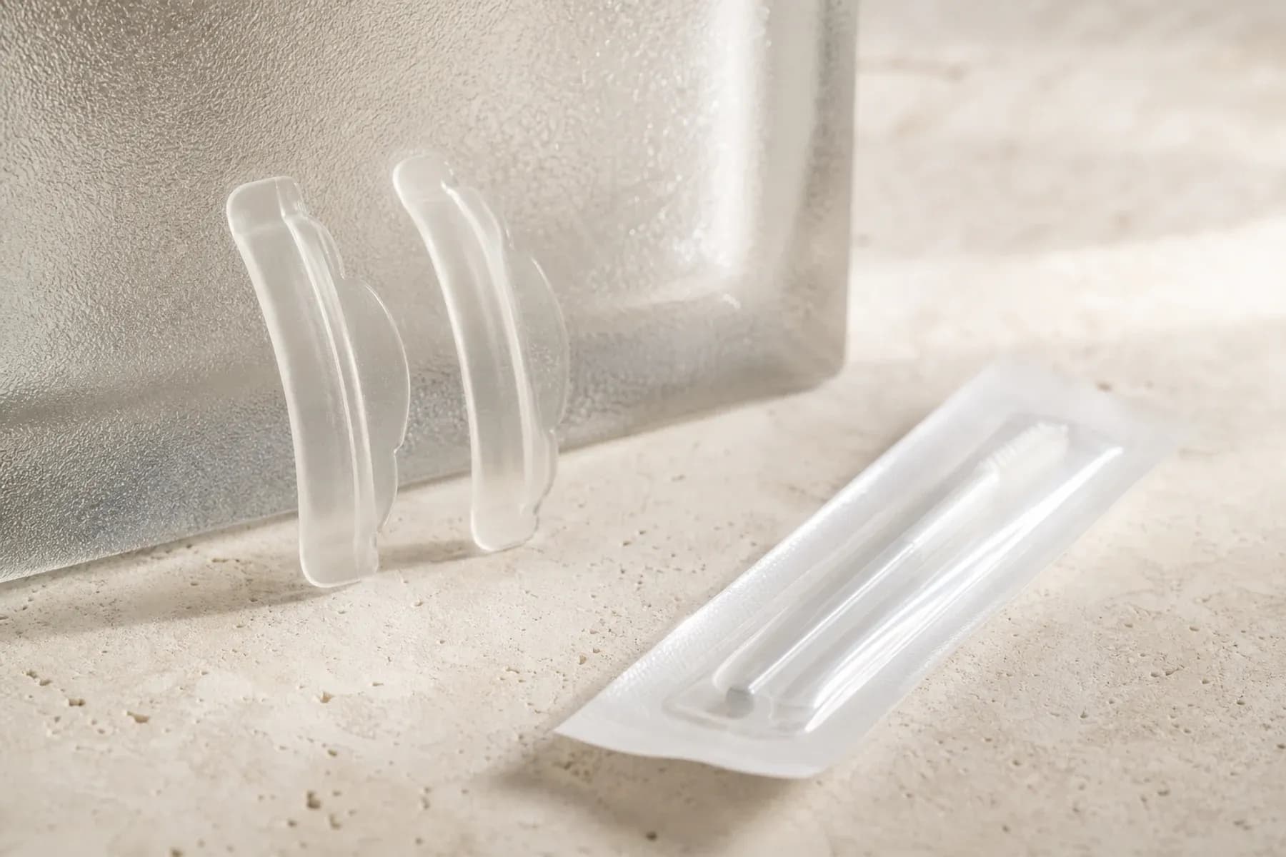 Lash Lift treatment materials arranged in Sonder's restrained ivory and forest-green visual style.
